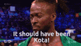 a man in a green wrestling outfit says " it should have been kota "