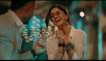 a woman wearing glasses is laughing while a man holds her hand