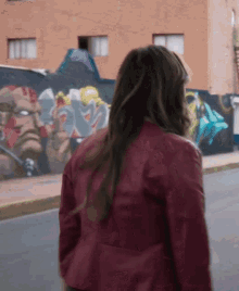 a woman in a red jacket walks down a street