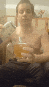 a man without a shirt is pouring a can of beer into a glass