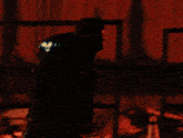a dark room with a fence and a fire in the background