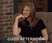 a woman is sitting on a couch with her hand on her chin and smiling .