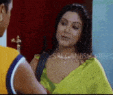 a woman in a yellow saree is talking to a man