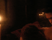 a man is laying on a woman 's shoulder with candles in the background