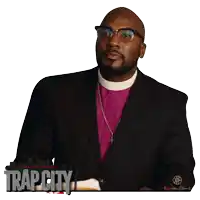 a man in a black suit and purple clergy robe is sitting in front of a trap city poster