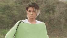 a man wearing a green sweater is holding something in his hand