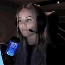 a woman wearing headphones and a microphone is sitting in front of a computer screen .