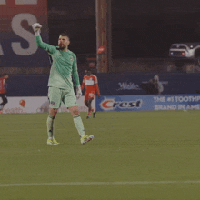 a soccer player holds up his fist in the air in front of a banner that says the # 1 toothpaste brand in america