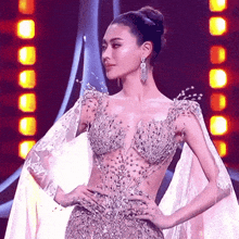 a woman in a dress with a cape is standing in front of a stage .