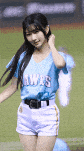 a girl wearing a blue hawks jersey and shorts