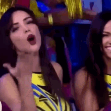 two women are standing next to each other in a dark room . one of the women is making a funny face .