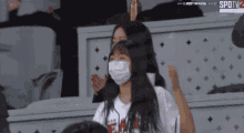 a woman wearing a mask is watching a baseball game on spot tv