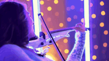 a woman is playing a violin in front of a purple background