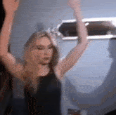 a woman is dancing with her arms in the air in a room .