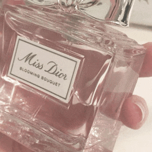 a person is holding a bottle of miss dior blooming bouquet perfume
