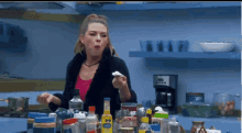 a woman is standing in a kitchen surrounded by bottles and jars including one that says 00 on it