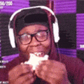 a man wearing headphones is eating a piece of food .