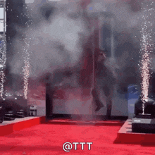 a man is walking on a red carpet with smoke coming out of the door