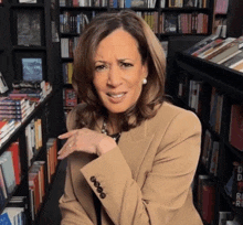 a woman in a tan jacket is sitting in front of a book shelf with a book titled freedom on it