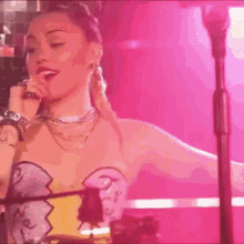 a woman is singing into a microphone on a stage in a pink room .
