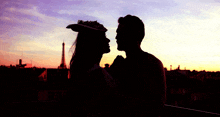 a silhouette of a man and woman kissing in front of the eiffel tower