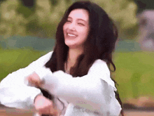 a woman in a white shirt is laughing with her arms outstretched
