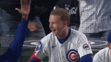 a man wearing a cubs jersey high fives another player
