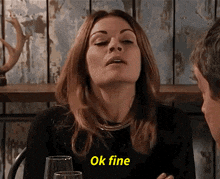 a woman is sitting at a table with a man and says ok fine