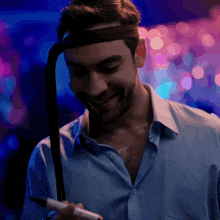 a man wearing a headband is holding a marker and smiling