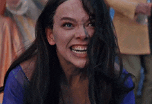 a woman with long black hair is smiling and making a funny face