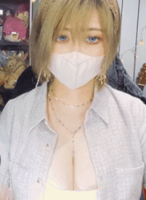 a woman with blonde hair and blue eyes wearing a white mask and a necklace
