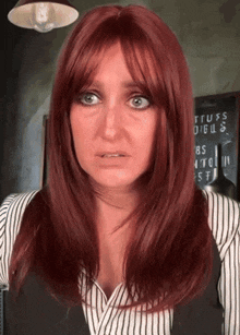 a woman with red hair stands in front of a sign that says tuffs