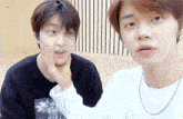 two young boys are standing next to each other and one is touching the other 's face ..
