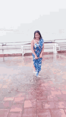 a woman in a blue dress is walking in the rain