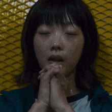 a close up of a man 's face with his hands folded in prayer
