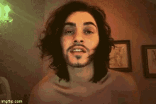a man with long hair and a beard is smiling for the camera .