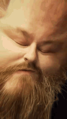 a man with a beard is making a funny face with his eyes closed