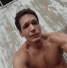 a shirtless man with a beard looks at the camera with his eyes closed