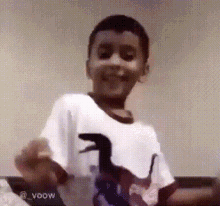 a young boy in a white shirt with a dinosaur on it