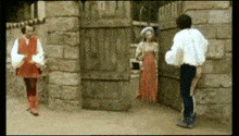 a man in a white shirt is standing next to a woman in an orange dress