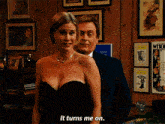 a woman in a black dress stands next to a man in a suit and says " it turns me on "