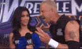 a wrestler talks to a woman in front of a sign that says wrestlemania