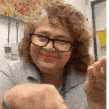 a woman wearing glasses and red lipstick is smiling and making a funny face .