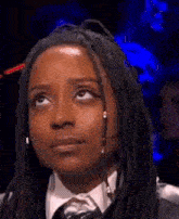 a woman with dreadlocks wearing a suit and tie is looking up .