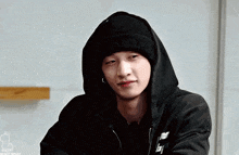 a young man wearing a black hoodie and a black hat is looking at the camera .