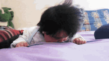 a baby is crawling on a bed with a stuffed animal in the background