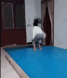 a person squatting on a blue mat in a room