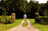 a man in a blue shirt is running down a dirt path