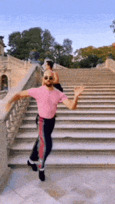 a man in a pink shirt is dancing on stairs .