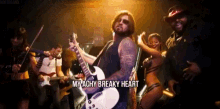 a man playing a guitar with the words " my achy breaky heart " below him